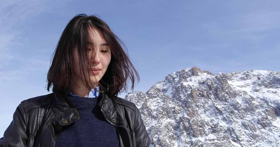 A Chinese woman with a snowy mountain backdrop.