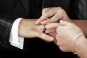 A woman putting on her groom’s wedding ring.