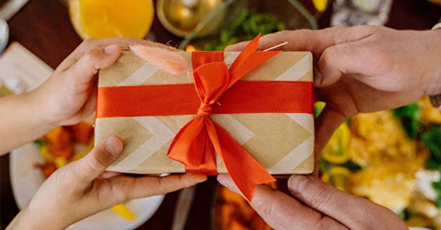 A closed-up photo of two people using both hands in holding the gift.